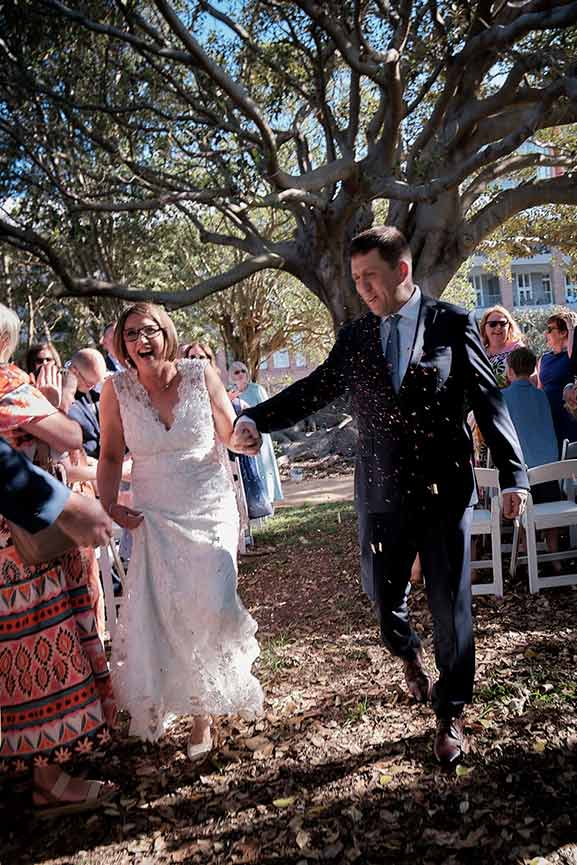 Bride and groom smiling during their first dance as the wedding guests look on