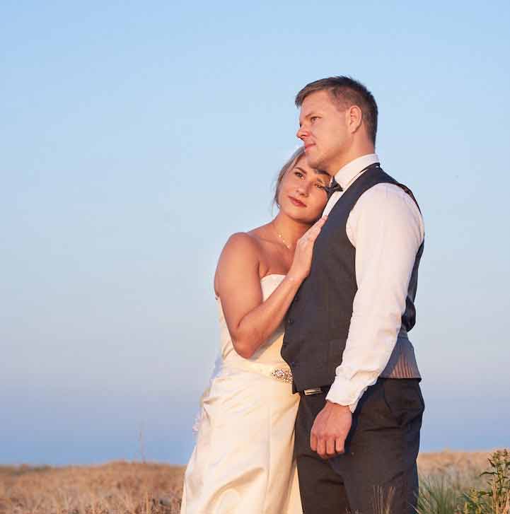 Bride rests on grooms chest as they stand close and enjoy the view in the distance