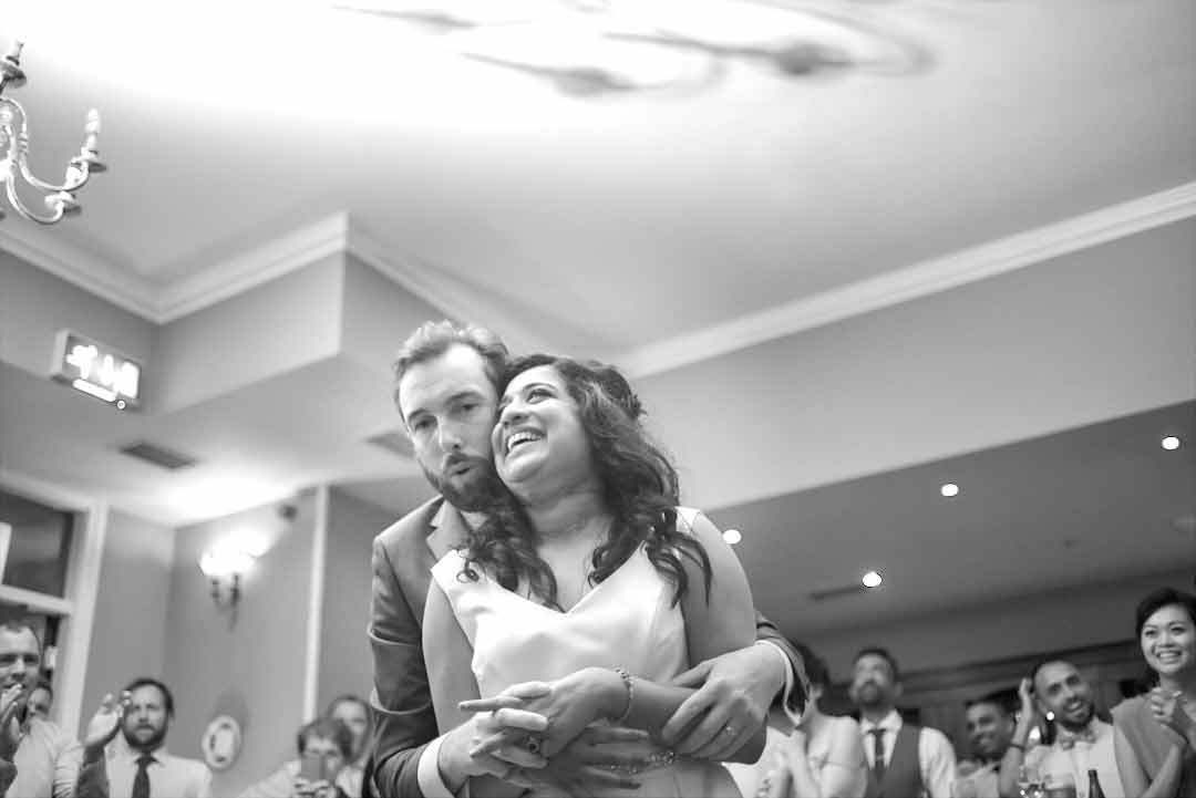 Groom hugs bride from behind during their first dance